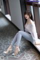 A woman sitting on a window sill wearing high heels.