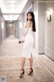 A woman in a white dress standing in a hallway.