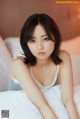 A woman laying on top of a bed in a white dress.