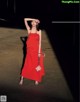 A woman in a red dress standing in a dark room.