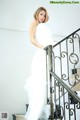 A woman in a white dress standing on a set of stairs.