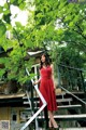 A woman in a red dress standing on a set of stairs.