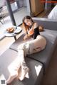 A woman sitting on top of a couch next to a table.