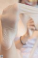 A woman in a white shirt is holding a pair of white socks.