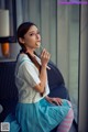 A woman sitting on a chair eating a lollipop.