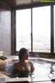 A woman sitting in a hot tub in front of a window.