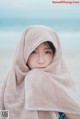 A little girl wrapped up in a towel on the beach.