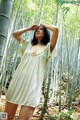 A woman in a white dress standing in a bamboo forest.